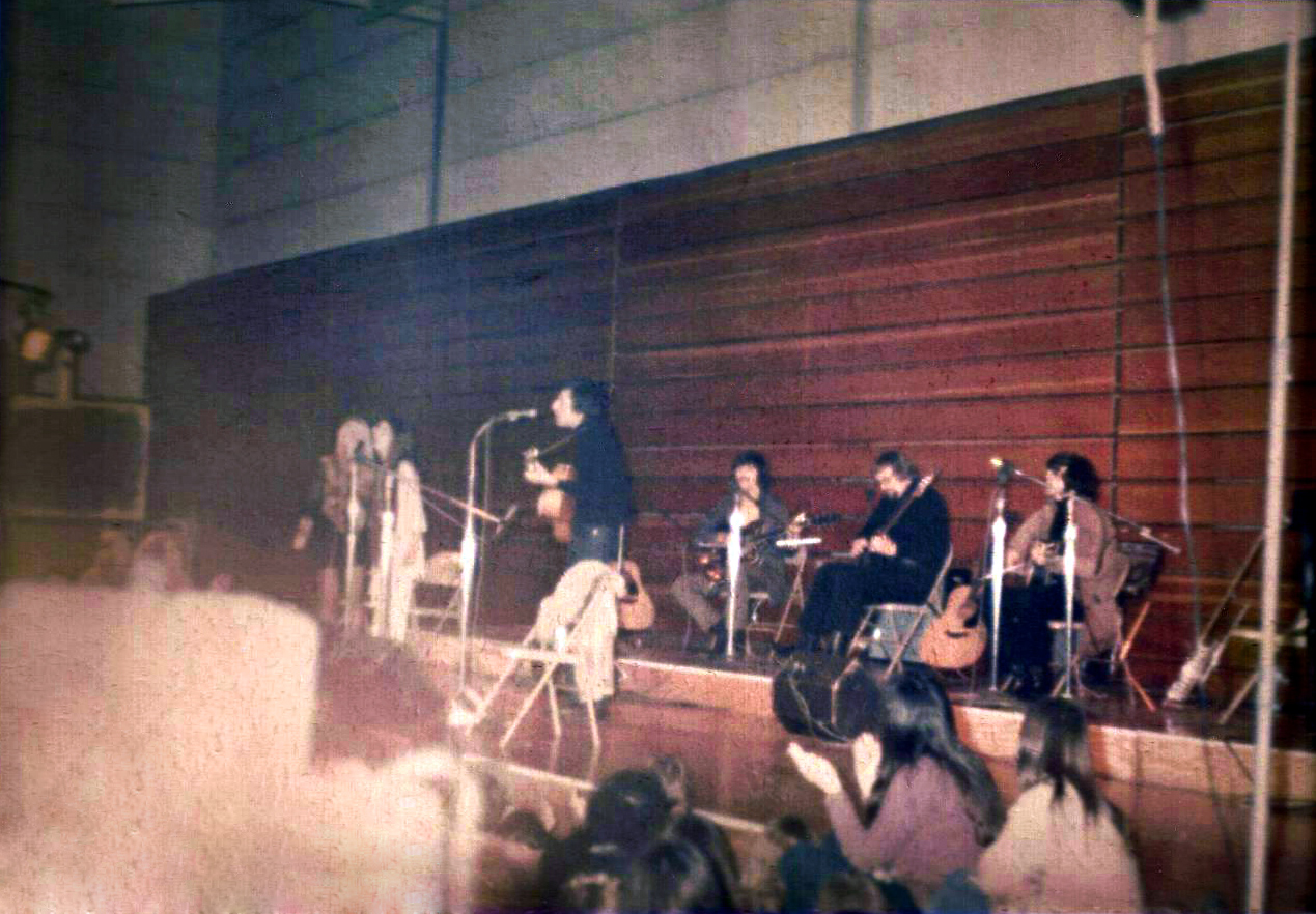 Earliest known photo of Leonard Cohen with his 1970 band (later known as The Army) in concert. Note Cohen's coat draped across a folding chair in front of him on the stage.